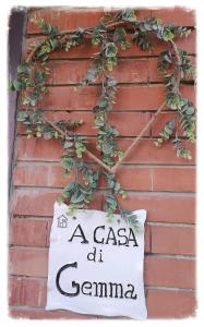 ein Schild an der Seite einer Ziegelmauer mit einer Pflanze in der Unterkunft A CASA DI GEMMA in Bologna