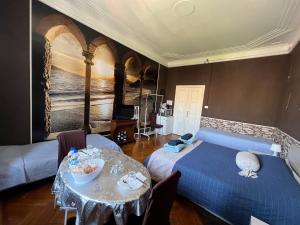 ジェノヴァにあるB&B Piazza della Vittoriaのベッドルーム1室(青いベッド1台、テーブル、絵画付)