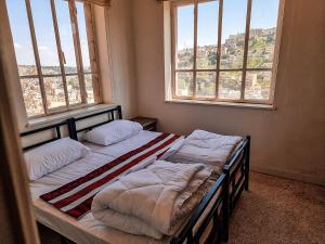 2 Betten in einem Zimmer mit 2 Fenstern in der Unterkunft Rainbow House in Amman