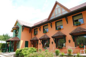 un edificio naranja con ventanas y plantas. en l'Auberge des Gourmets Hôtel Restaurant en Le Vaudioux