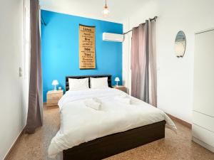 1 dormitorio con 1 cama grande y pared azul en SOHO Artsy 55sqm apt with Acropolis view, en Atenas