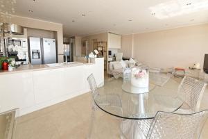 een keuken en een woonkamer met een glazen tafel en stoelen bij CANNES Vue Mer in Cannes
