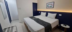 um quarto com uma cama branca com um cobertor preto em Copacabana Blue Hotel no Rio de Janeiro