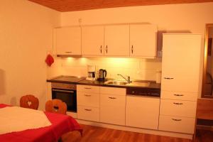 eine Küche mit weißen Schränken, einem Waschbecken und einem Bett in der Unterkunft Ferienwohnung Schwarzwald in der Pension Glöcklehof in Todtnau