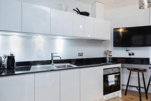 a white kitchen with a sink and a microwave at Designer Penthouse Notting Hill with Terrace sleeps Five in London