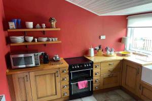 cocina roja con fogones y microondas en Viking Cottage, en Arrochar
