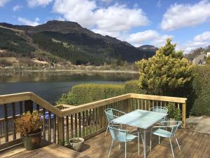 a table and chairs on a deck with a view of a lake at Viking Cottage in Arrochar