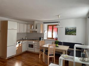 une cuisine avec des placards blancs, une table et une salle à manger dans l'établissement Apartment Krämerhaus Annaberg, Dachstein West, à Annaberg-Lungötz