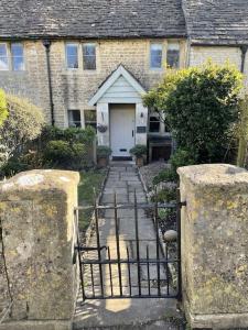 a stone house with a gate and a white door at HEBE COTTAGE - Idyllic and homely with attention to detail in Atworth