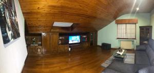 sala de estar con techo de madera y TV en El Rincón del Único en Oviñana