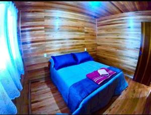 Habitación pequeña de madera con cama en la sauna en Casa de Campo Machado, en Urubici