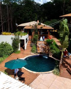 a swimming pool with an umbrella in a yard at Estância Peti in Barão de Cocais