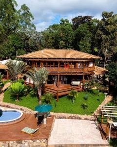 バラン・デ・コカイスにあるEstância Petiの大きな木造の家で、目の前にプールがあります。