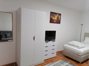 um quarto branco com uma cómoda branca e uma televisão em Apartman Radulović em Kladovo