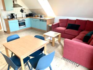 a living room with a red couch and a table and chairs at Vineta Ferienwohnungen in Mölschow