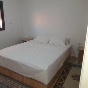 Schlafzimmer mit einem Bett mit weißer Bettwäsche und Kissen in der Unterkunft RESIDENCE OUARZAZATE in Ouarzazate