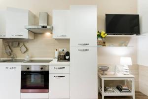 パレルモにあるCATHEDRAL APARTMENTの白いキャビネットと壁掛けテレビ付きのキッチン