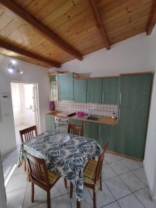uma cozinha com mesa e cadeiras e uma cozinha com armários verdes em Ponente em Donnalucata