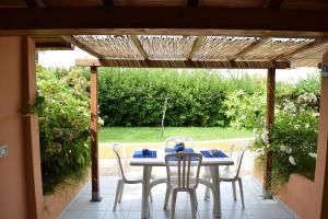 uma mesa e cadeiras sentadas sob uma pérgola de madeira em Villaggio La Perla em Marina di Camerota