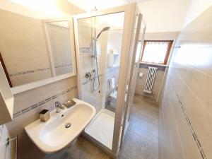 y baño blanco con lavabo y ducha. en Il Glicine sul Garda Appartamento Turistico en Peschiera del Garda