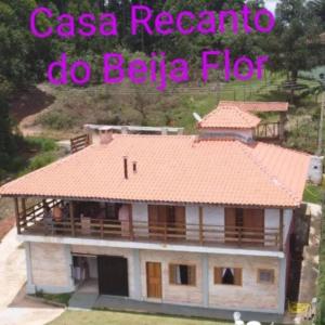 蒙特沃德的住宿－Casa Recanto Beija Flor, Monte Verde，一座有橙色屋顶的房子,上面写着csa reactivo do beta flu