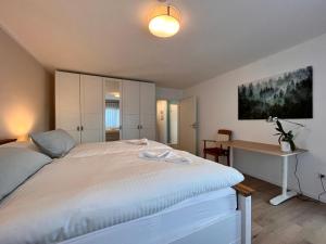 a bedroom with a white bed and a desk at Auszeit im Gartenweg in Neuweiler