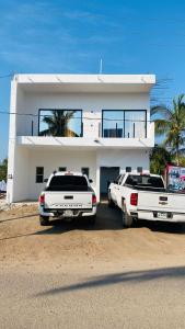 dos autos estacionados frente a una casa blanca en Bungalows del Mar En Punta Perula- Casa Tory, en Pérula