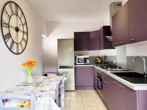 een keuken met paarse kasten en een grote klok aan de muur bij ***Maison de 38m² -400m Plage- avec Jardin*** in Le Brusc