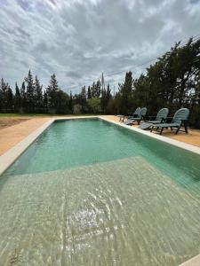 a large swimming pool with two chairs at Agradable casa de campo con piscina en la Barrosa in Chiclana de la Frontera