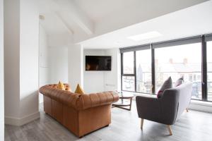 a living room with a brown leather couch and two chairs at Fabulous Penthouse, Brilliant Location, Sleeps 6! in Belfast