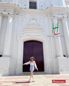 Una donna in piedi di fronte a un palazzo di Hotel Libano a León