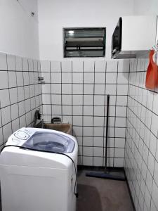 a white tiled bathroom with a washing machine at Suíte 08 - Aconchegante e Exclusiva in Cuiabá