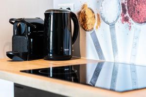 czarny dzbanek do kawy siedzący na ladzie z łyżkami pomiarowymi w obiekcie Luxe en ruim vakantiehuis voor 4 personen. w mieście Nieuw-Lekkerland