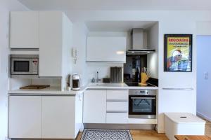 eine weiße Küche mit weißen Schränken und Geräten in der Unterkunft Superbe appartement 4 personnes Arcachon Abatilles avec parking 500m plage Péreire in Arcachon + 17 Fotos