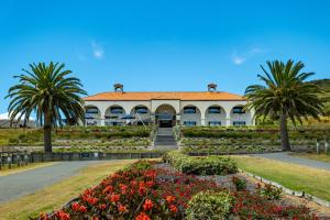 un edificio con un jardín con flores y palmeras en Carrington Estate en Tokerau Beach