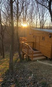 eine Holzhütte im Wald mit Sonnenuntergang in der Unterkunft Őzlak Lombház in Zalaújlak