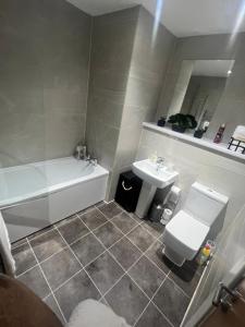 a bathroom with a tub and a toilet and a sink at Luxury Chic Apartments in Liverpool