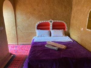 a bed with a red headboard and two towels on it at Dar Yaya in Mhamid