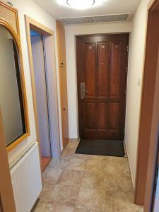 a hallway with a wooden door and a tile floor at Best Golf-Birdland Apartman in Bük