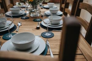 a wooden table with plates and wine glasses on it at Albert - 5 Bedrooms Sleeps 11 Parking Wi-Fi Contractors in Preston
