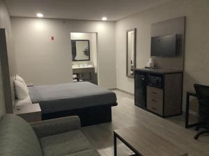 1 dormitorio con cama, sofá y TV en Americas Best Value Inn & Suites San Benito, en San Benito