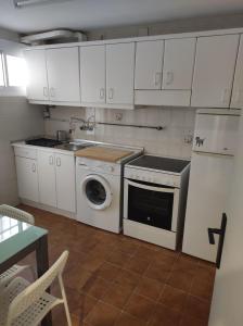 uma cozinha com armários brancos e uma máquina de lavar e secar roupa em Apartamento en zona céntrica y tranquila. em Pamplona