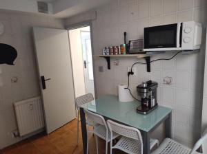 a kitchen with a table with a coffee maker and a microwave at Apartamento en zona céntrica y tranquila. in Pamplona