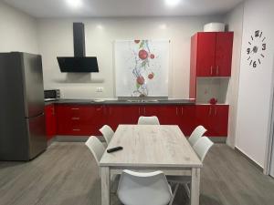 eine Küche mit roten Schränken und einem Tisch mit weißen Stühlen in der Unterkunft El descanso in Conil de la Frontera