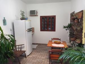 uma cozinha com uma mesa e um frigorífico branco em Suíte Cleo em Cabo Frio