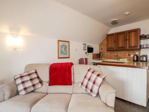 a living room with a couch and a kitchen at Greshornish Boathouse in Edinbain