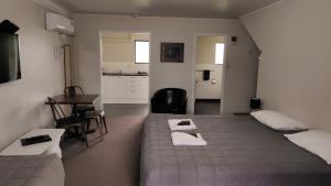 a bedroom with two beds and a table and a kitchen at Drury Motor Lodge in Drury