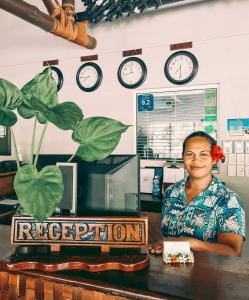 une femme assise sur un bureau avec des horloges sur le mur dans l'établissement Saletoga Sands Resort & Spa, à Matatufu