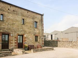 un edificio de ladrillo con un banco delante de él en Old Byre Cottage en Ravenstonedale