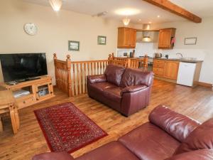 a living room with a couch and a tv at Old Byre Cottage in Ravenstonedale